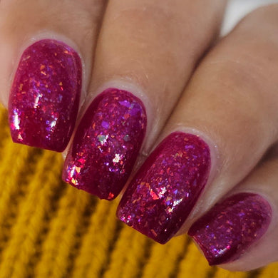 Close-up of a hand with pink glittery nail polish on a yellow textured background